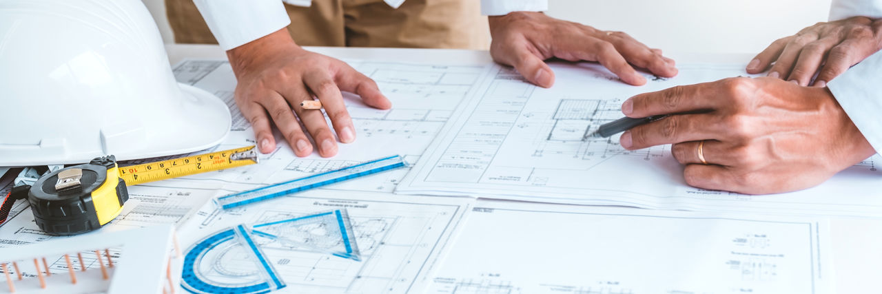 Midsection of architect working on blueprint in office