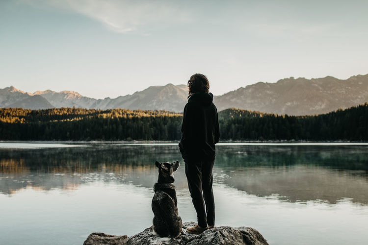 Rear view of man looking at lake against mountain range