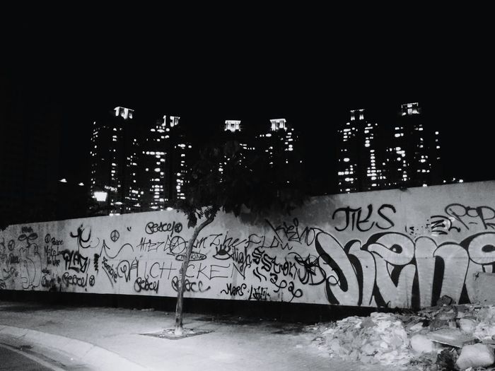 Illuminated graffiti on wall by buildings in city at night
