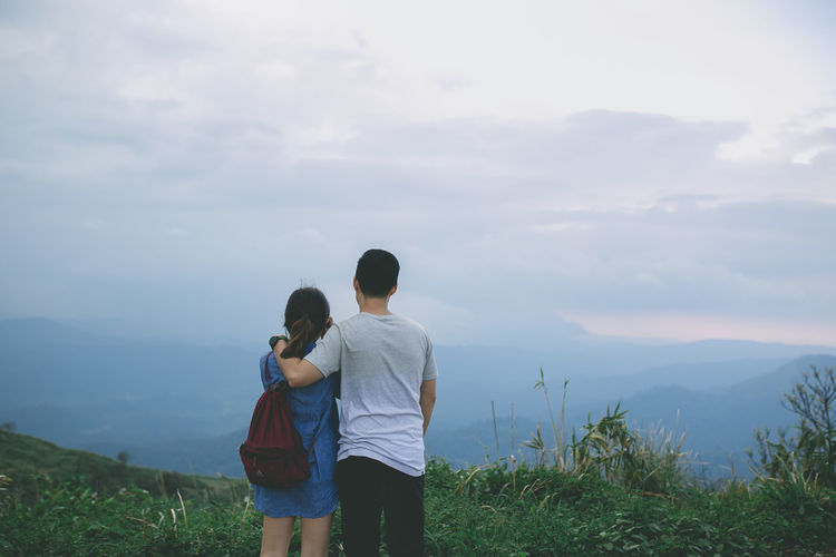 Rear view of couple standing on field against sky