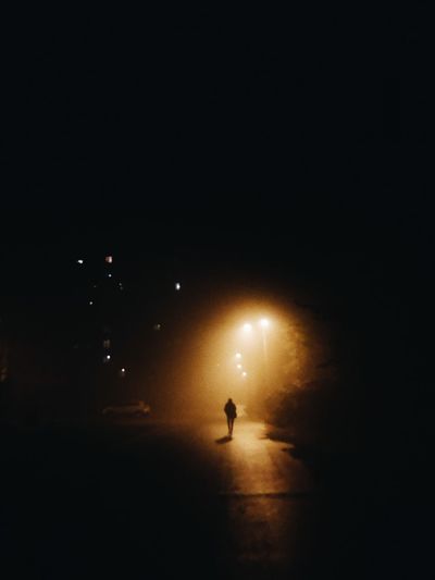 Silhouette person on illuminated street at night