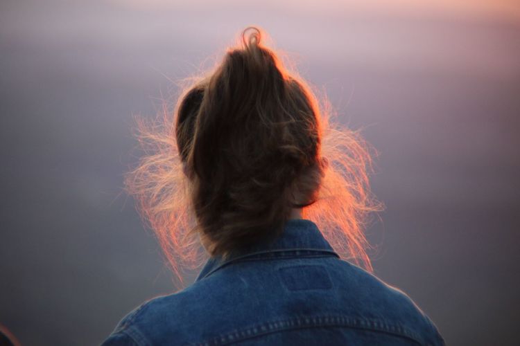 Rear view of woman with messy hair during sunset