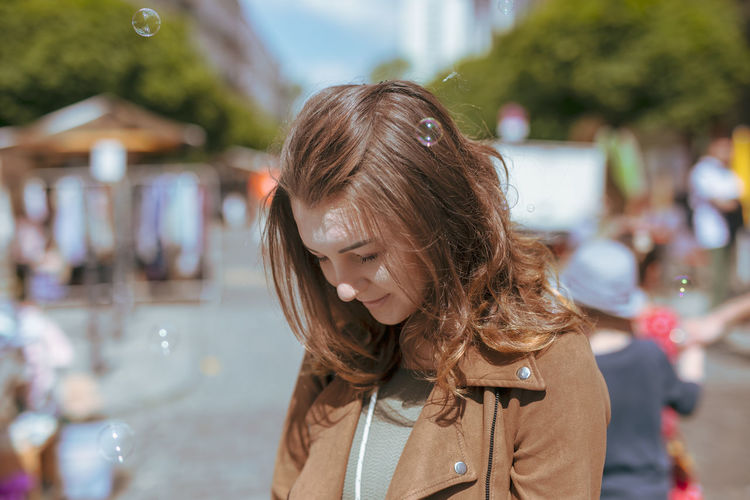 Young woman with eyes closed standing on street during sunny day