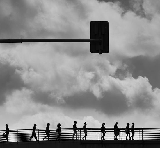 Low angle view of people by railing against sky