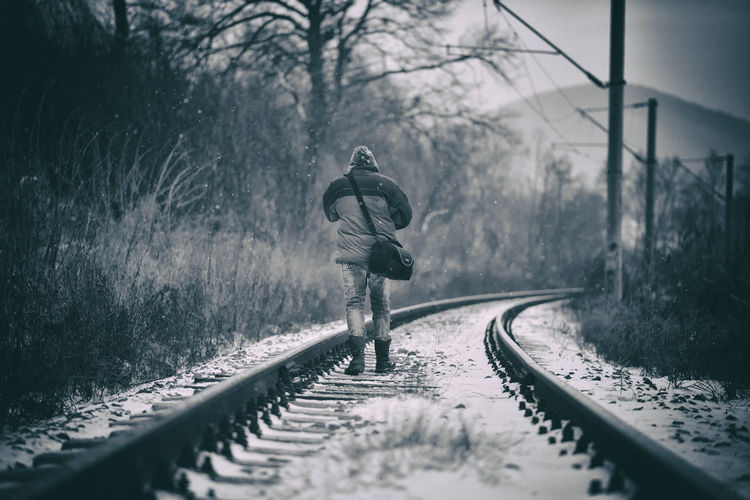 Man running on railroad track in winter