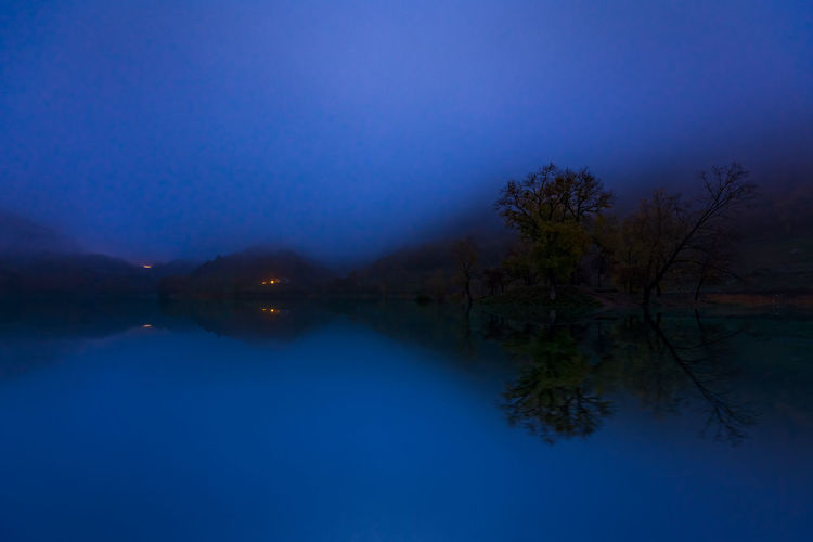Scenic view of lake against blue sky at dusk