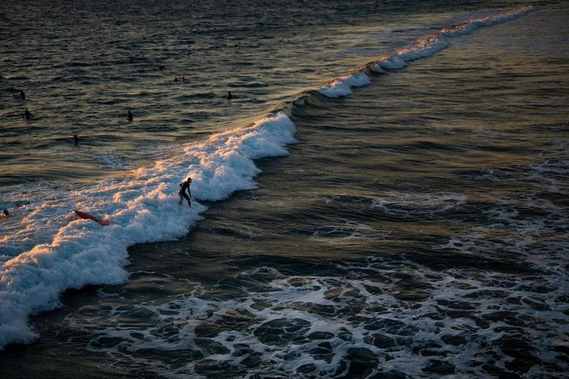 High angle view of man surfing on waves rushing towards shore