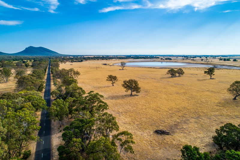 Straight rural highway leading to a mountain among fields and trees in australia