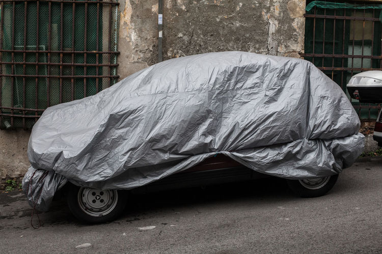 Car covered in tarpaulin on street