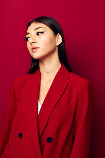 Portrait of young woman standing against yellow background