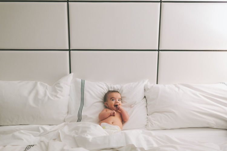 Portrait of baby boy lying on bed at home
