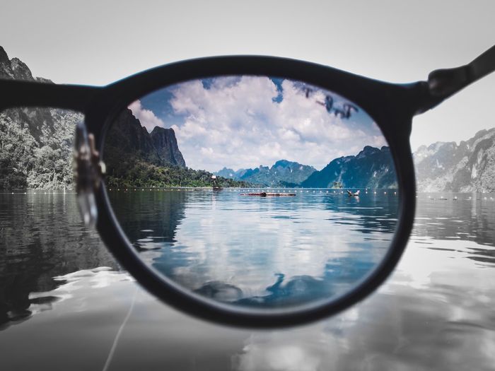 Reflection of sunglasses in lake against sky