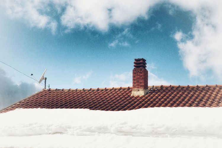 Snow covered roof and building against sky