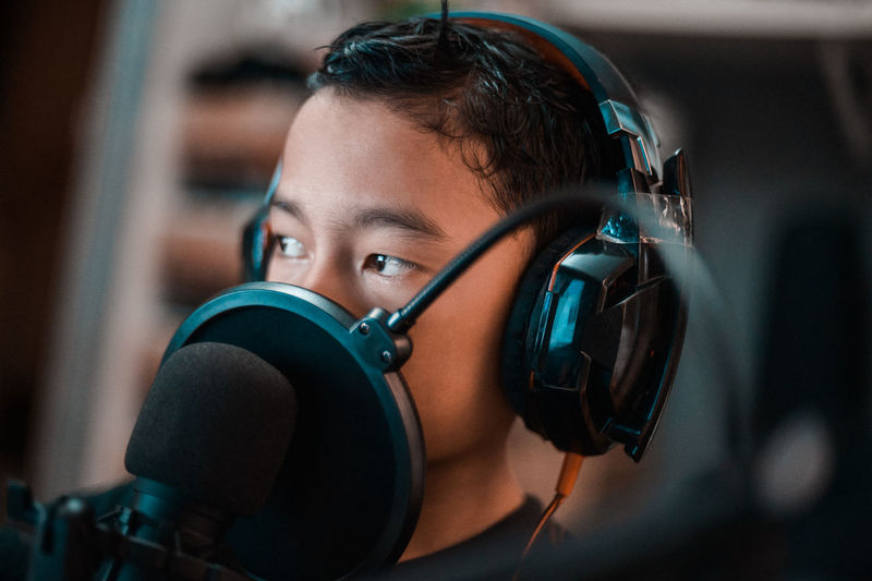 Close-up portrait of a boy wearing a headphone while live streaming