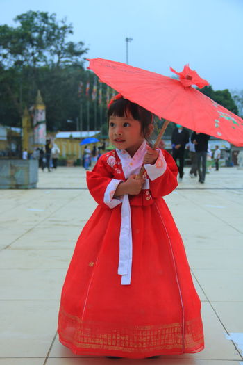 Cute girl standing with red umbrella
