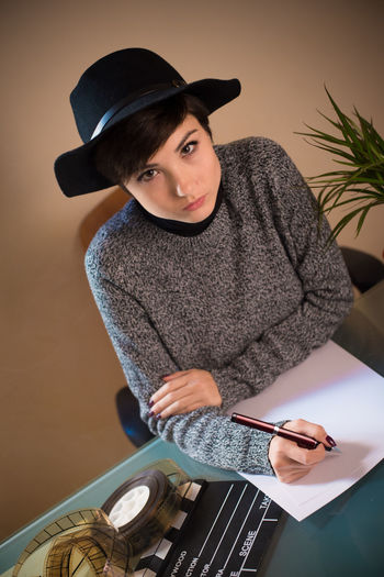 Portrait of female screenwriter writing on paper while sitting in office