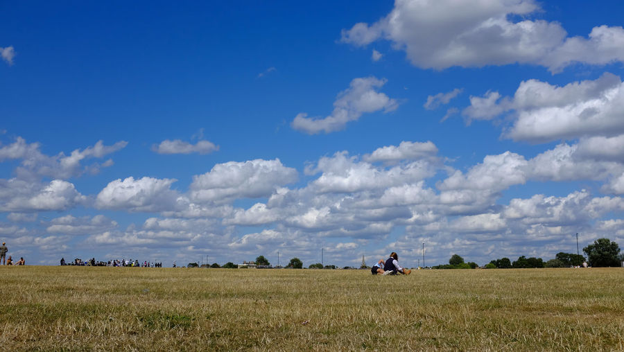 Couple sitting on field against sky
