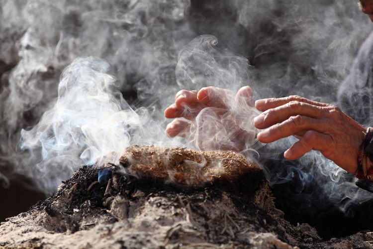 Cropped image of hand over smoke emitting from incense at temple