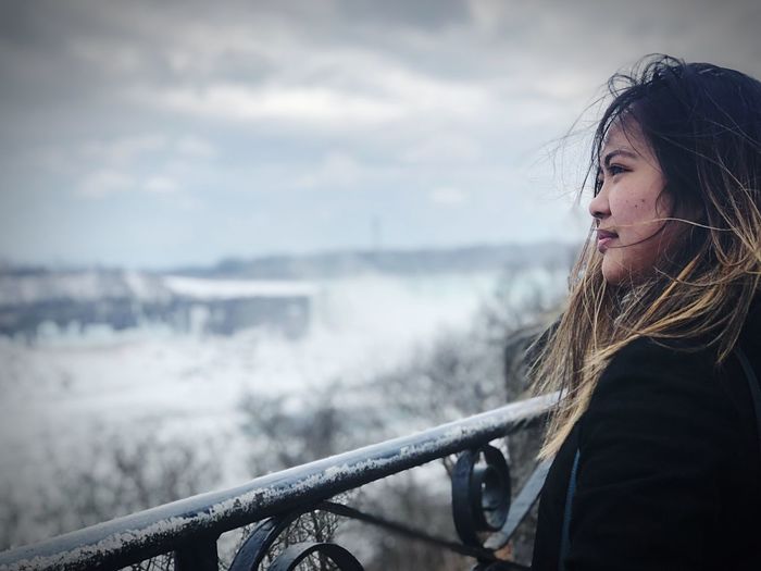 Woman looking away against sky during winter