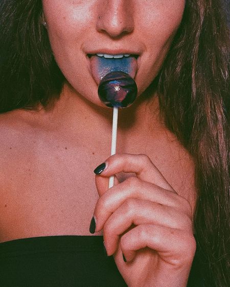Midsection of woman eating lollipop