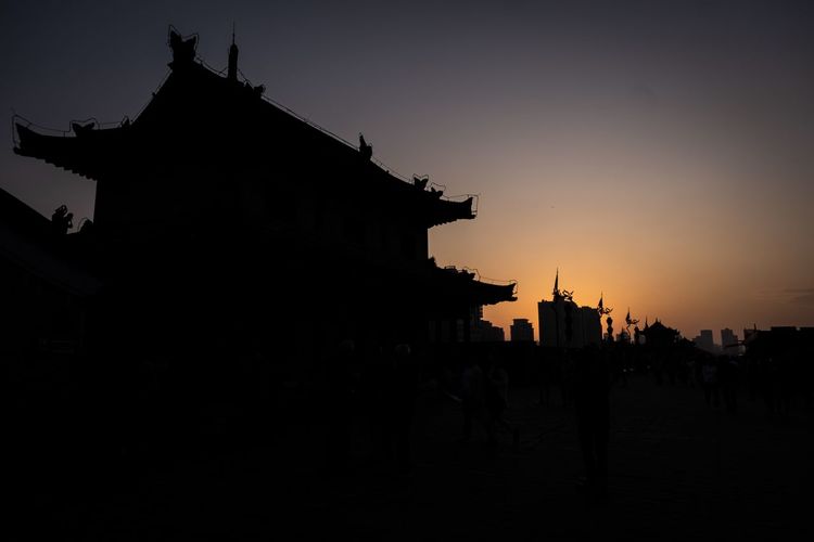 Silhouette buildings against clear sky at sunset