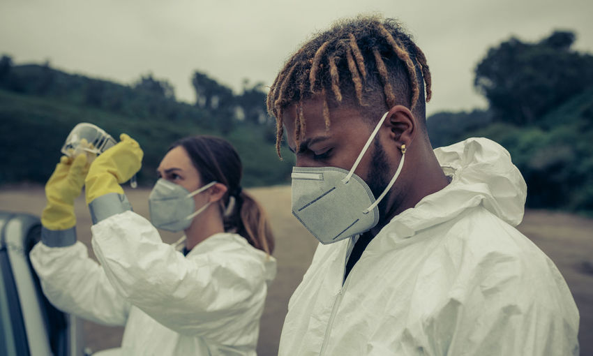 Man and woman wearing pollution mask while standing outdoors