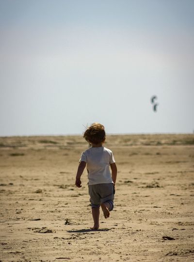 Rear view of boy walking on sand