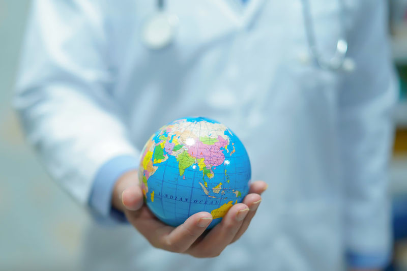 Midsection of doctor holding globe