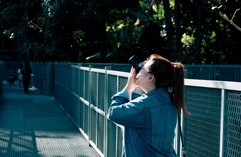 Woman photographing on footbridge