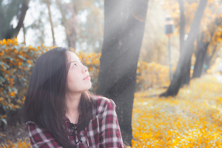 Low section of woman looking at forest during autumn