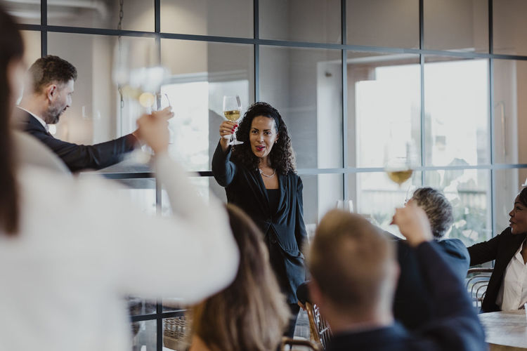 Cheerful business people toasting wineglasses during company party