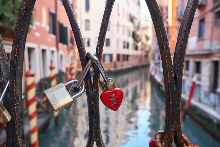 Combination red heart-shaped and other padlocks on the bridge in venice, italy. sunny day
