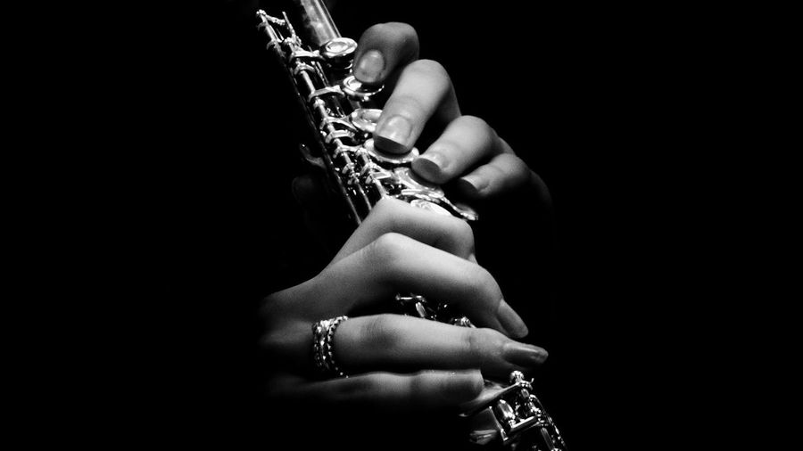 Cropped image of woman playing trumpet against black background