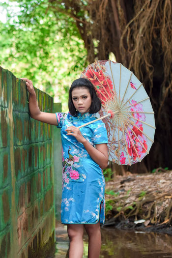 Full length portrait of smiling girl standing against wall