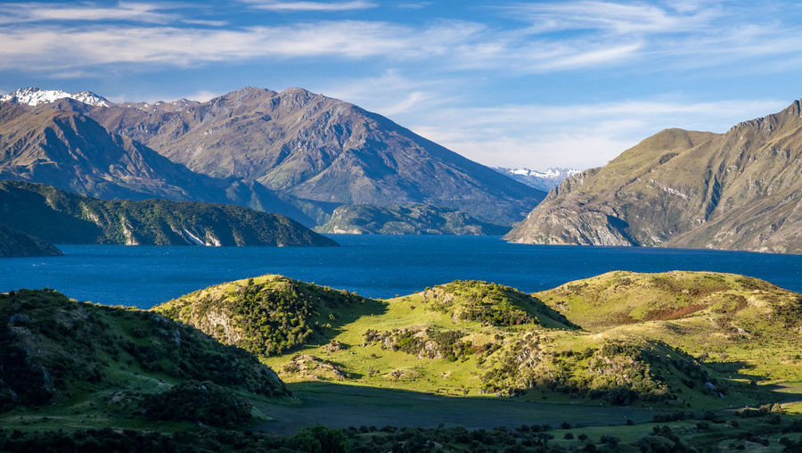Scenic view of lake by mountains against sky