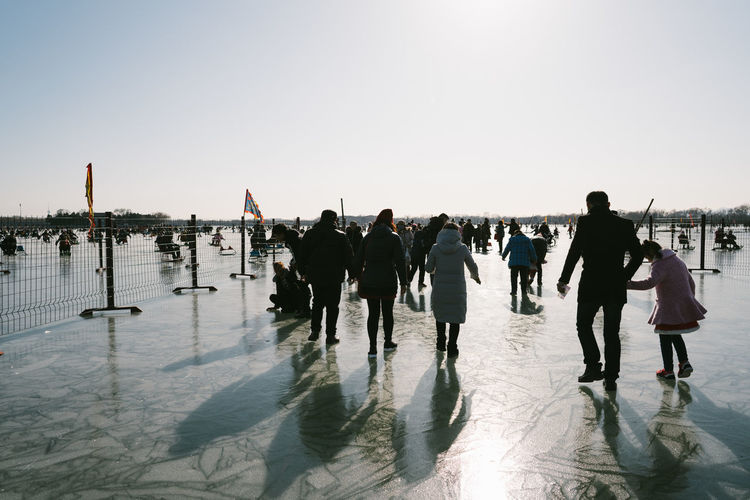Rear view of people walking on frozen lake