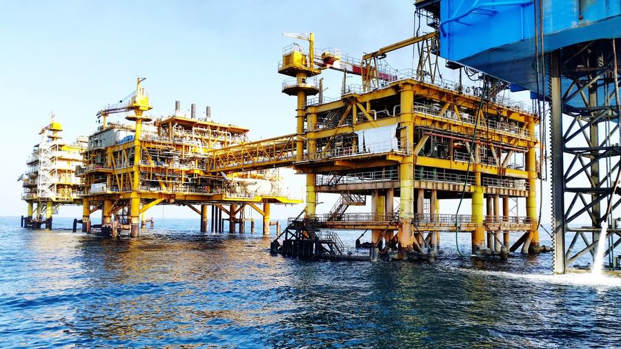 Drilling rigs in sea against sky