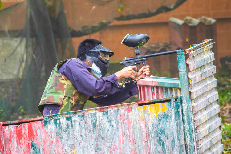 Man wearing protective gears playing with paintball gun
