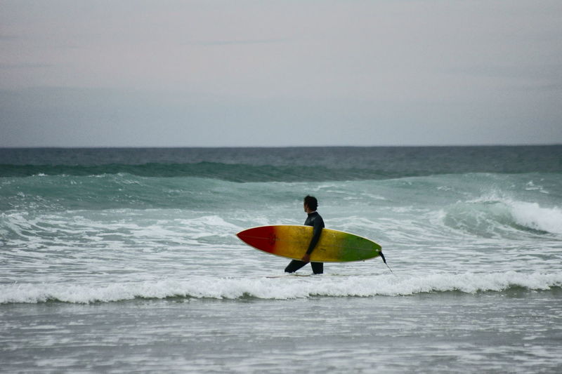 Man surfing on beach against sky