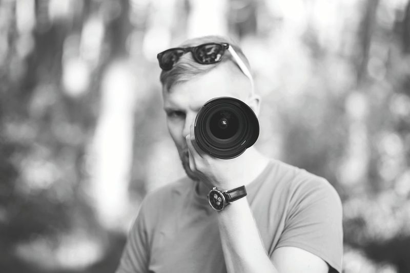 Portrait of photographer holding camera lens