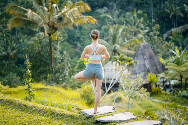 Woman doing yoga on stepping stone against trees