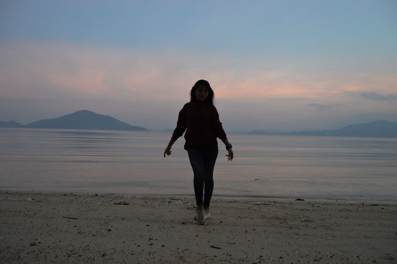 Full length of girl standing on beach during sunset. 