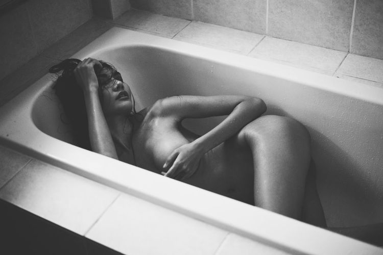 Seductive woman lying in bathtub