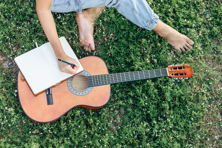 Low section of man playing guitar on field