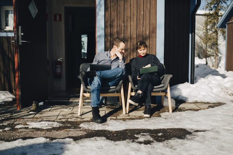 Male and female entrepreneurs discussing over tablet while sitting in front of vacation home