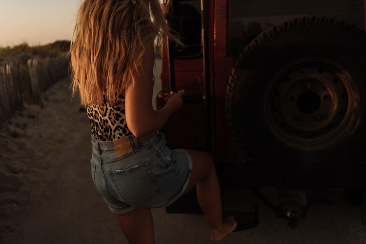 Rear view of a girl standing in a car
