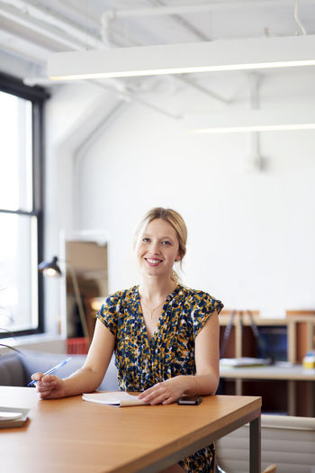 Portrait of smiling businesswoman sitting at table in office