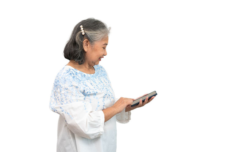 Side view of woman using smart phone against white background