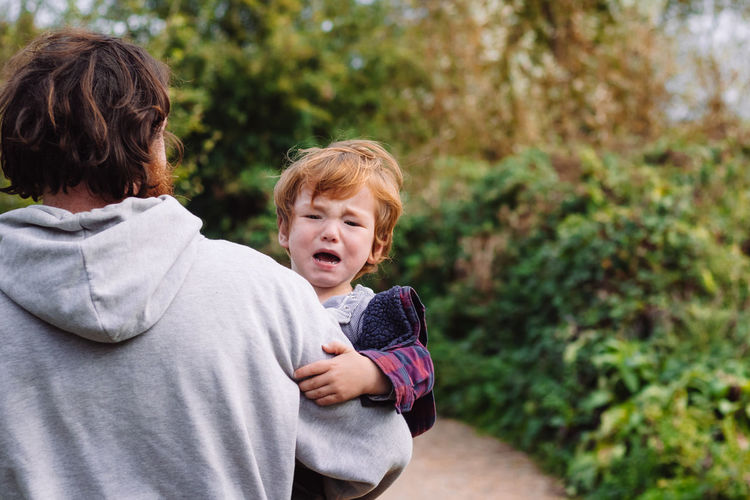 Father carrying his upset son away