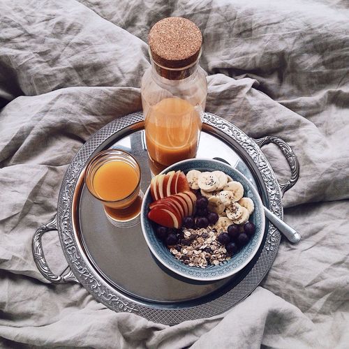 High angle view of muesli and mango juice in steel tray on bed